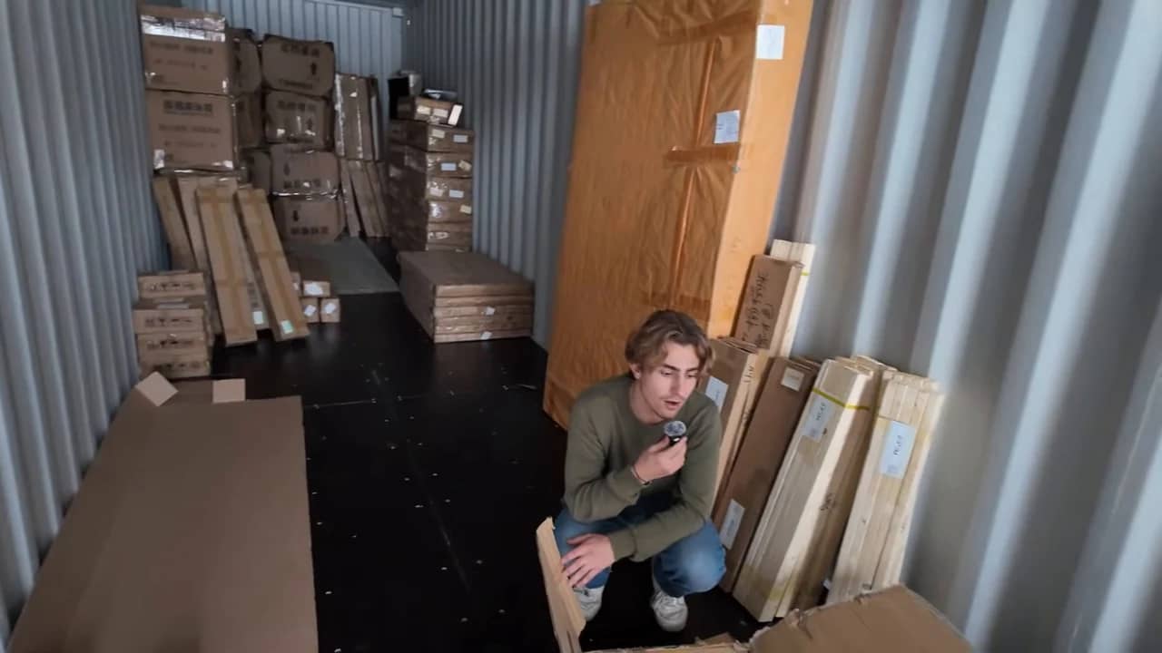 Des cartons et caisses de formes différentes dans un conteneur, avec une personne à réception.